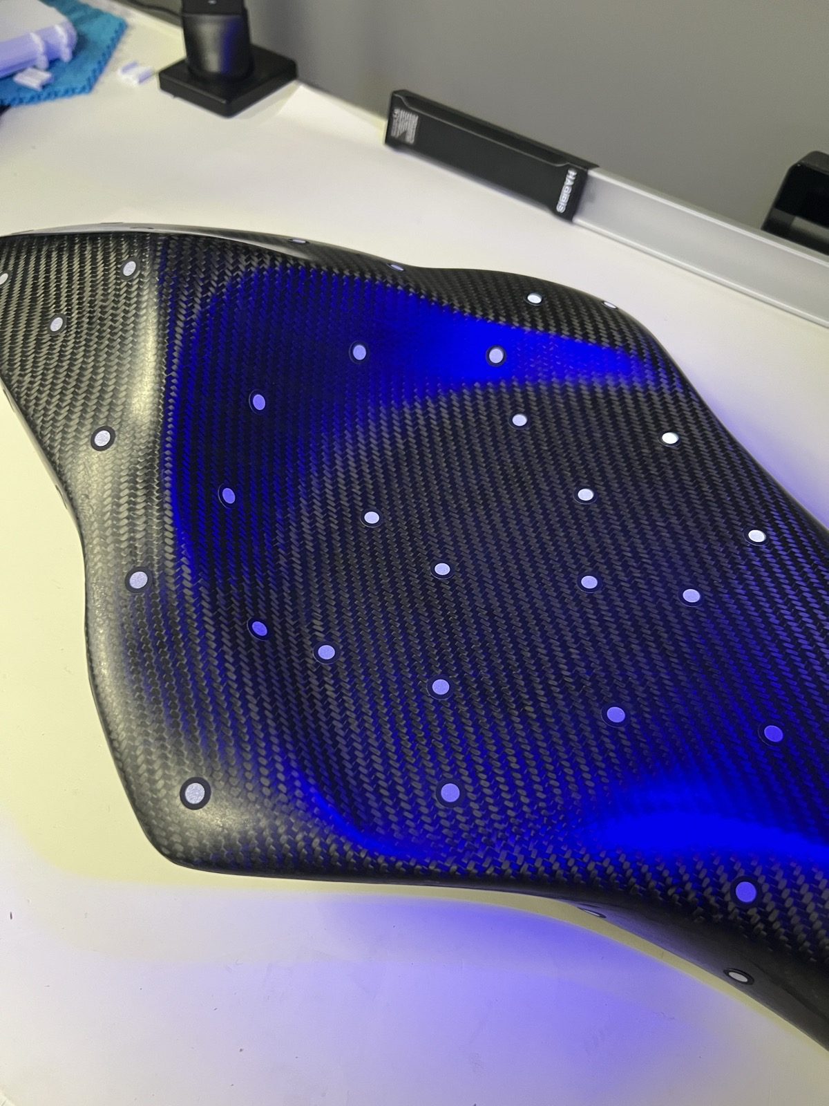 Carbon-fiber race motorcycle seat with reference dots under blue structured-light scanning