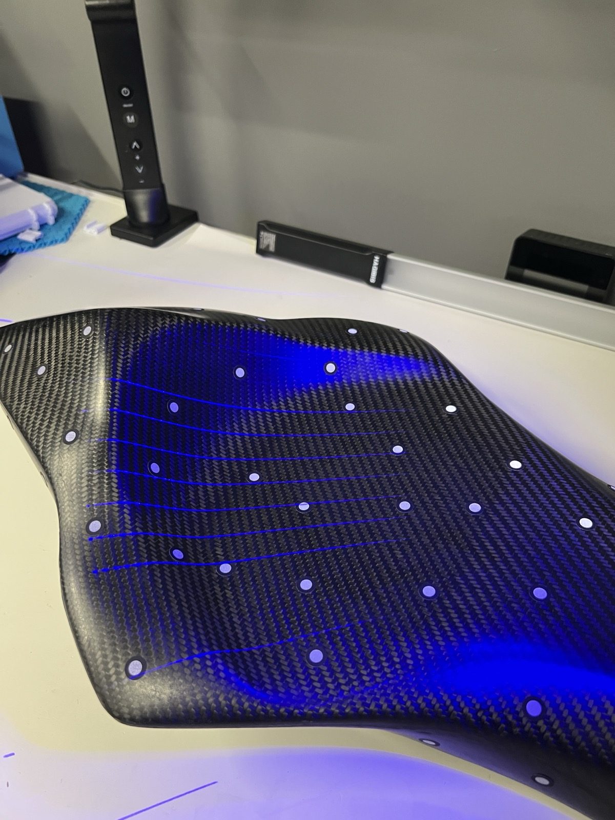 Structured-light lines sweep the organic carbon-fiber surface during the 0.2 mm scan.