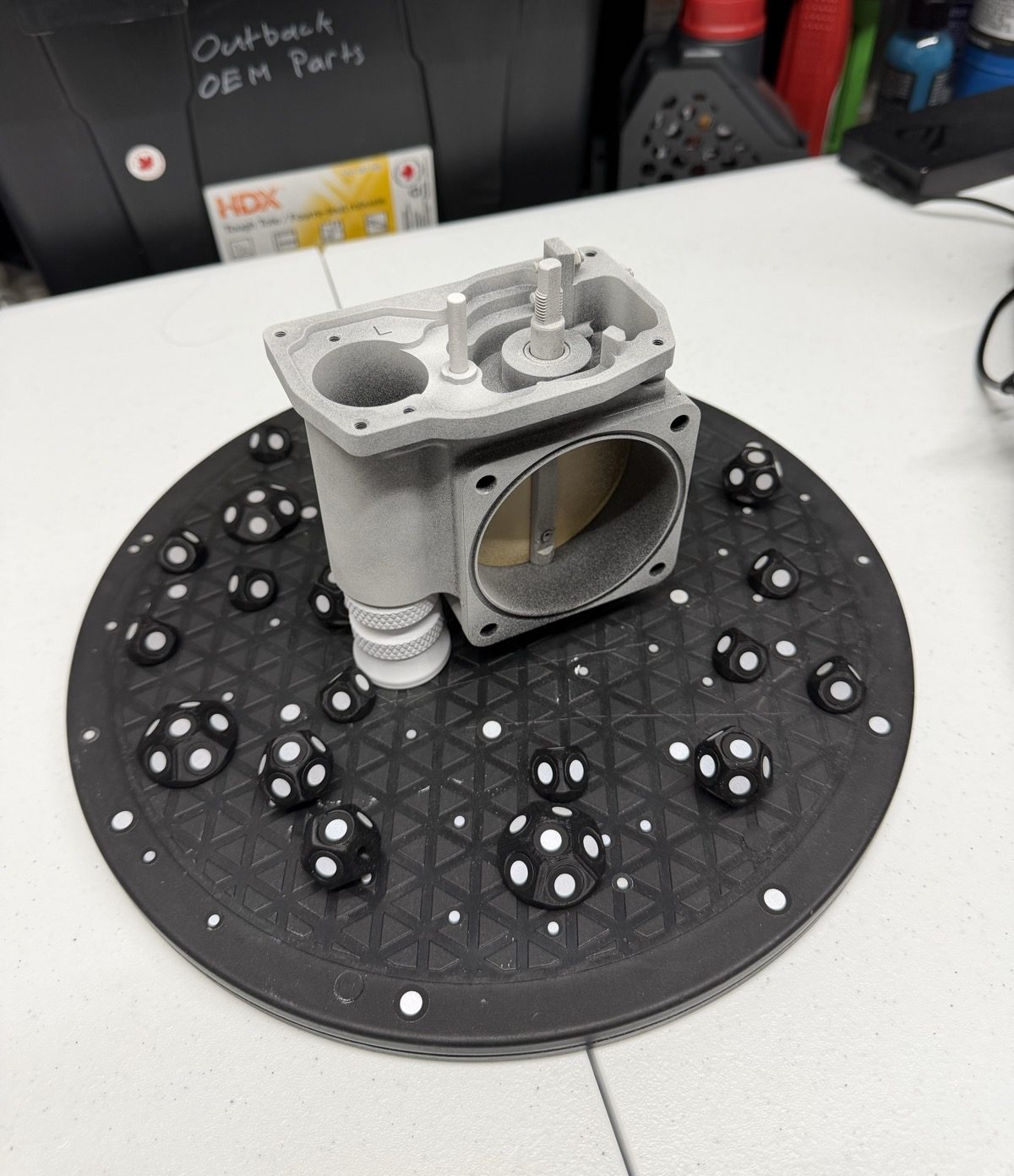 The billet throttle body staged on the turntable, prepped with matte spray and surrounded by reference markers.